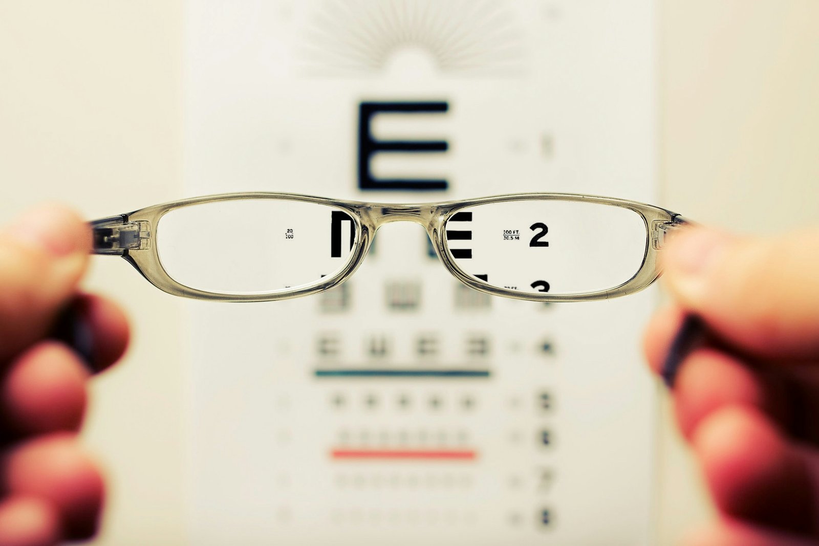 A hand holding a pair of eyeglasses